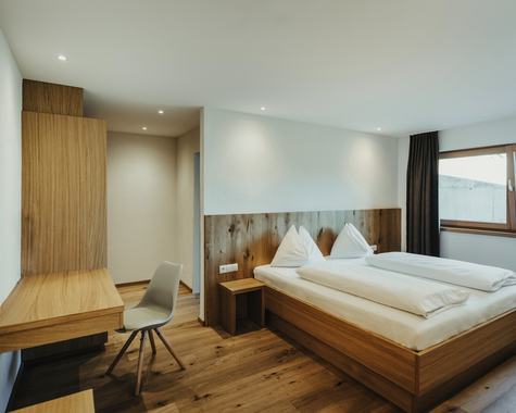 Schlafbereich mit Doppelbett, Schreibtisch und Fenstern