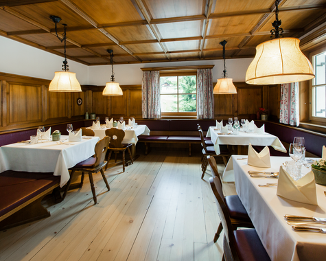 Gemütlicher Restaurantbereich mit Holzbalkendecke und gedeckten Tischen.