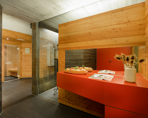 Moderner Wellnessbereich mit rotem Tisch und Holzverkleidung. 