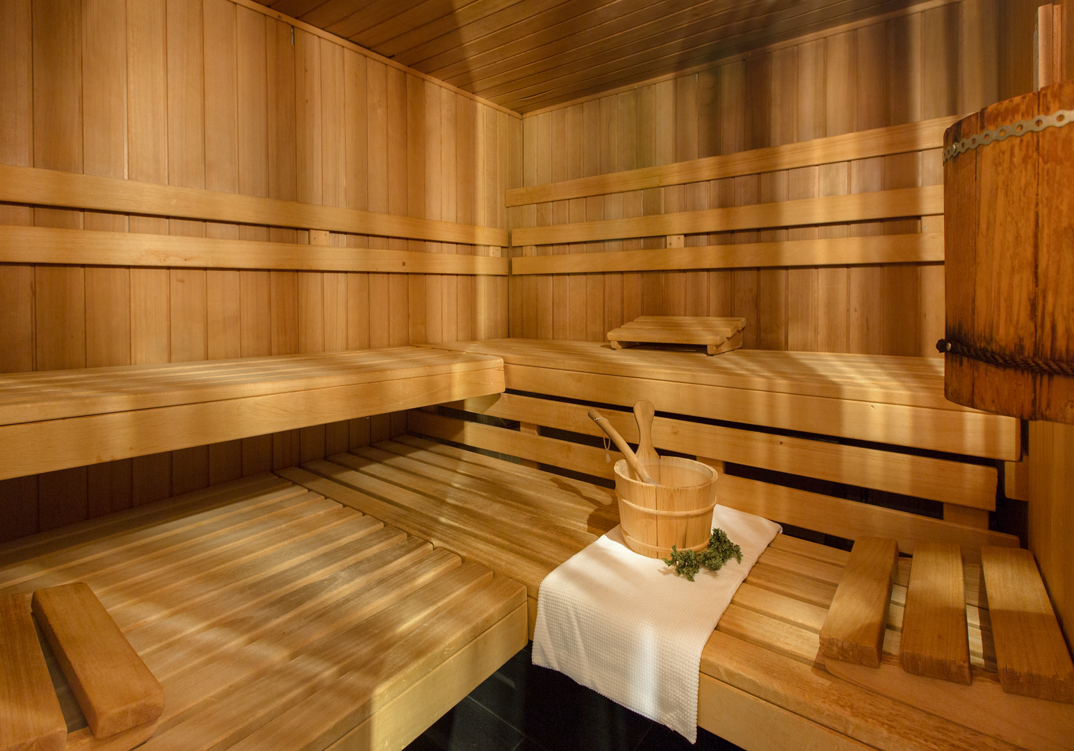 Helle Holzsauna mit mehreren Sitzbänken und warmer Beleuchtung.