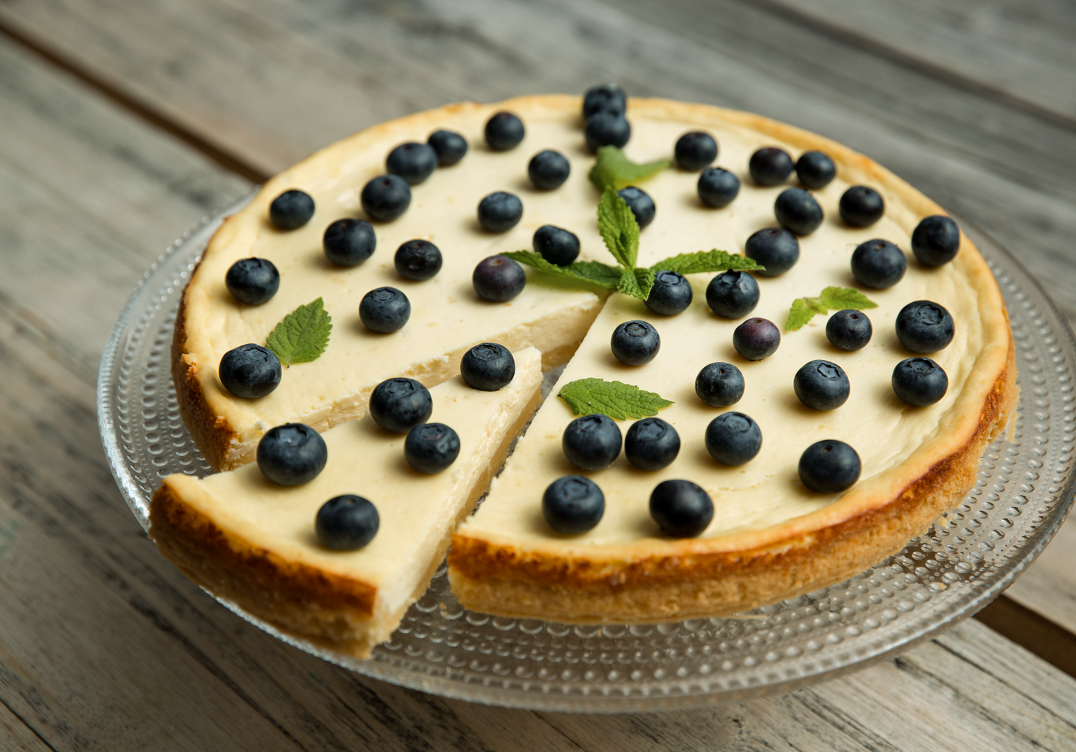 Frisch gebackener Käsekuchen mit Blaubeeren auf einem Holztisch.