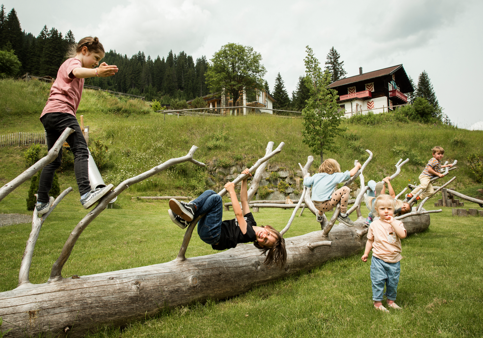 Kinder balancieren und spielen auf Baumstämmen in einem naturnahen Spielbereich.