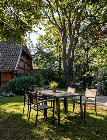 Garten mit Tisch und Stühlen unter einem Baum im Halbschatten
