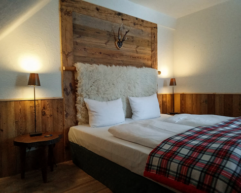 Doppelbett mit Holzkopfteil, karierten Kissen und Wandleuchten