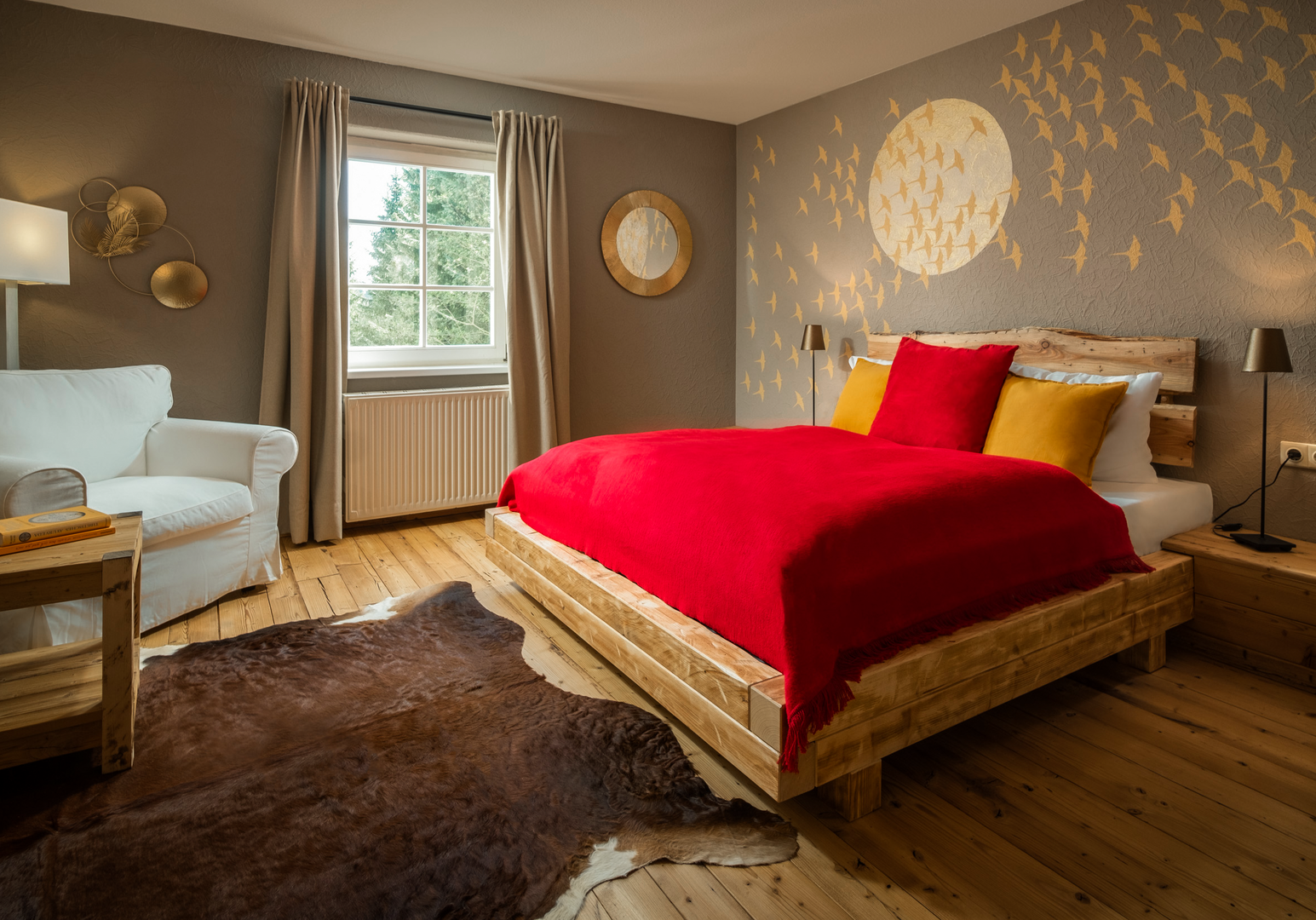 Doppelbett mit roter Decke, gelbem Kissen und dekorativem Wandmotiv