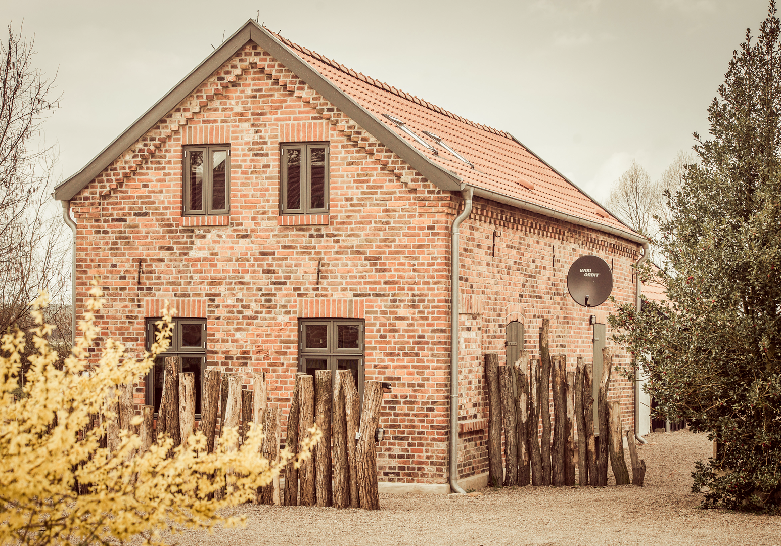 Steinhaus mit Zaun und Büschen 