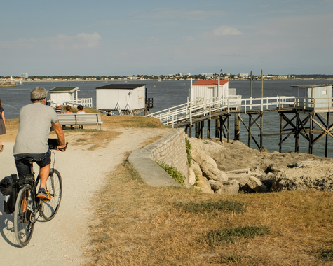 Radfahrer auf einem Weg oberhalb eines Strandes mit Blick auf das Meer