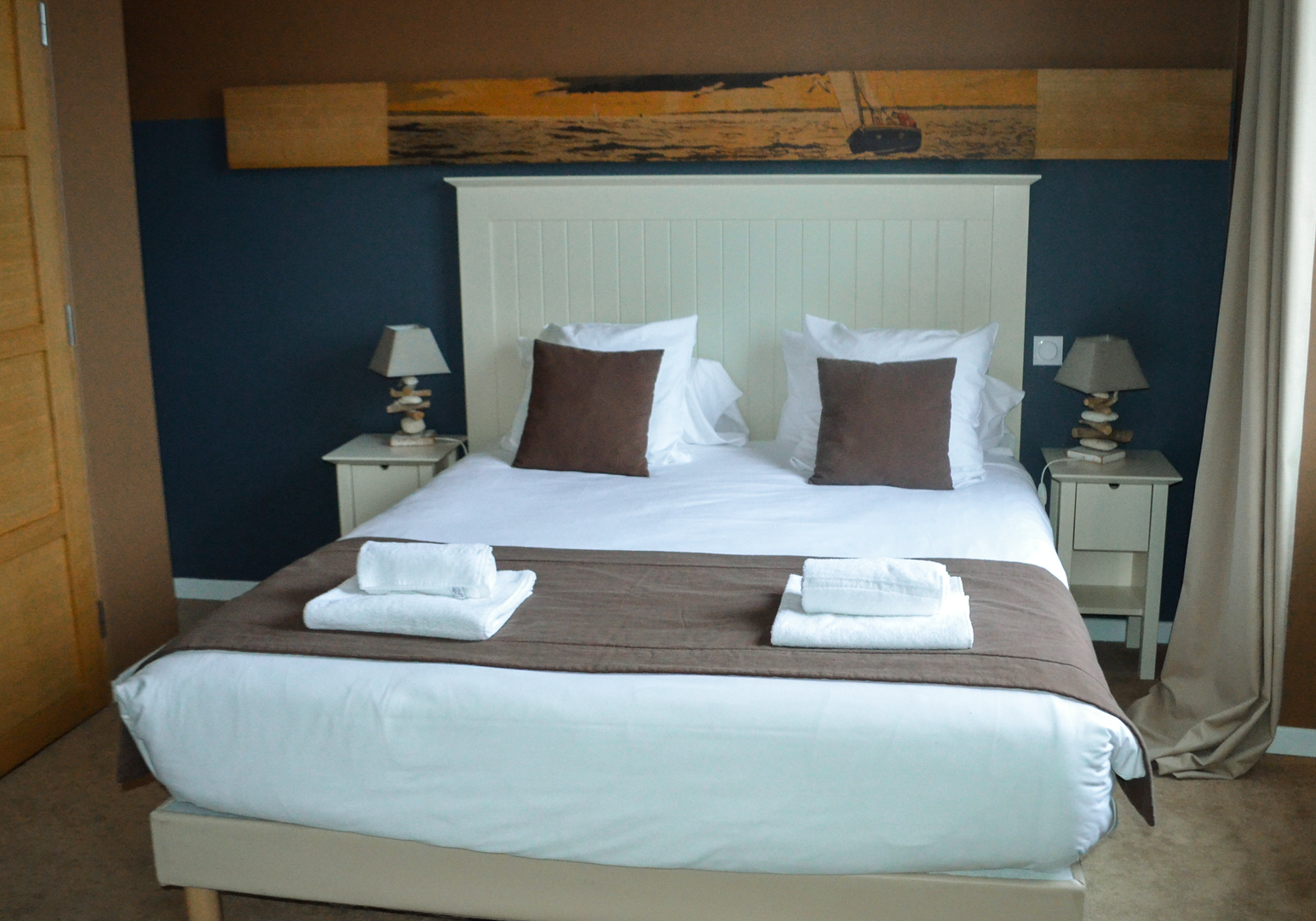 Doppelbett mit weißem Holzkopfteil, blauer Wand und Nachttischlampen