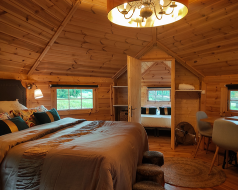Holzchalet-Innenraum mit Doppelbett, Kronleuchter und TV