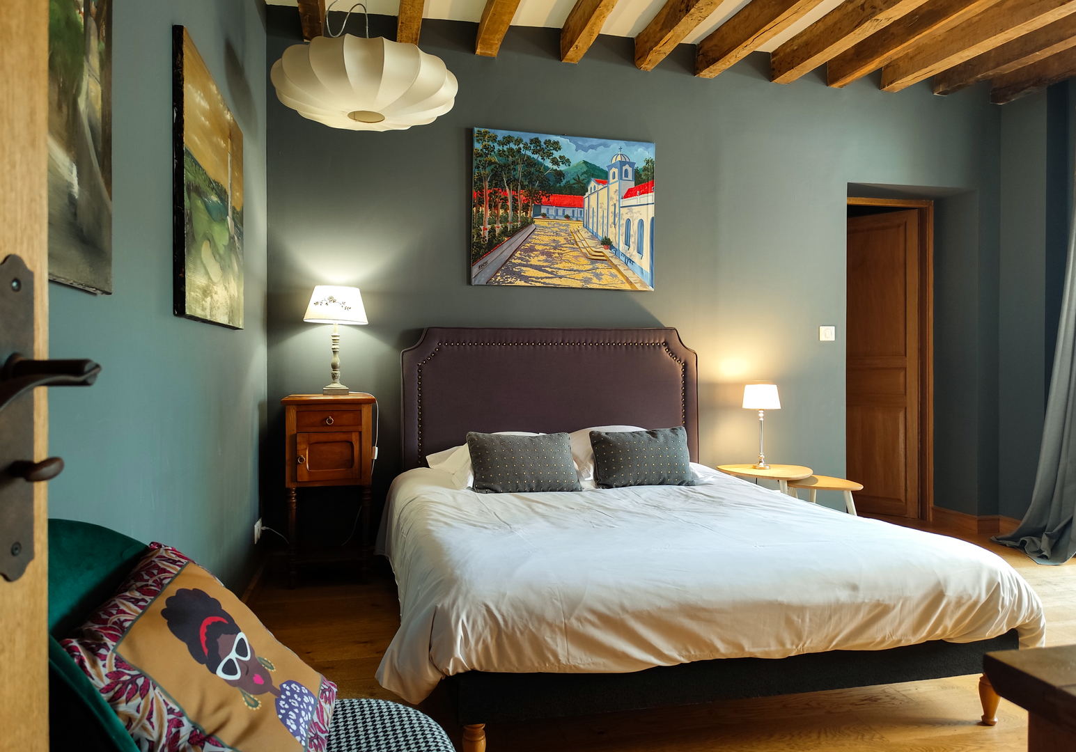 Schlafzimmer mit Doppelbett, Holzbalken und bunten Kissen