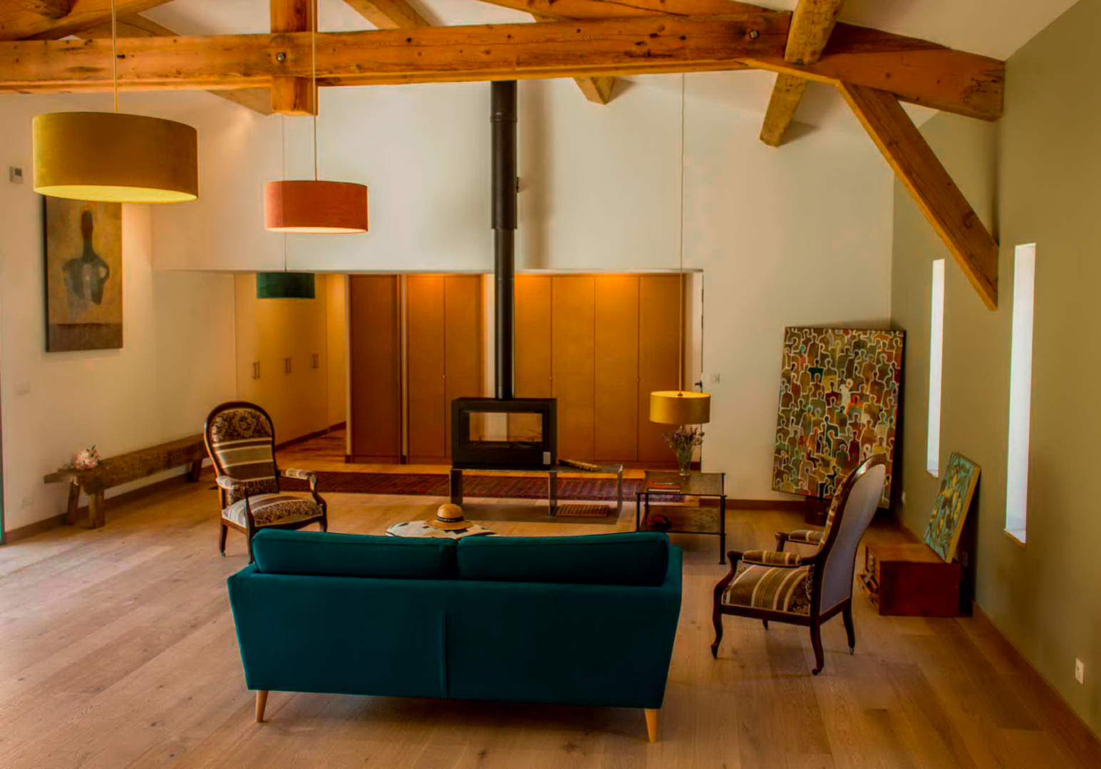 Wohnbereich mit Kaminofen, türkisem Sofa und Holzboden