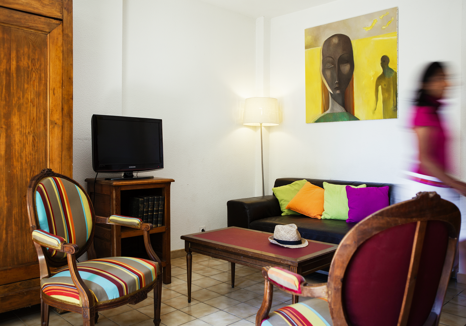 Wohnzimmer mit TV, bunten Stühlen und afrikanischem Wandbild