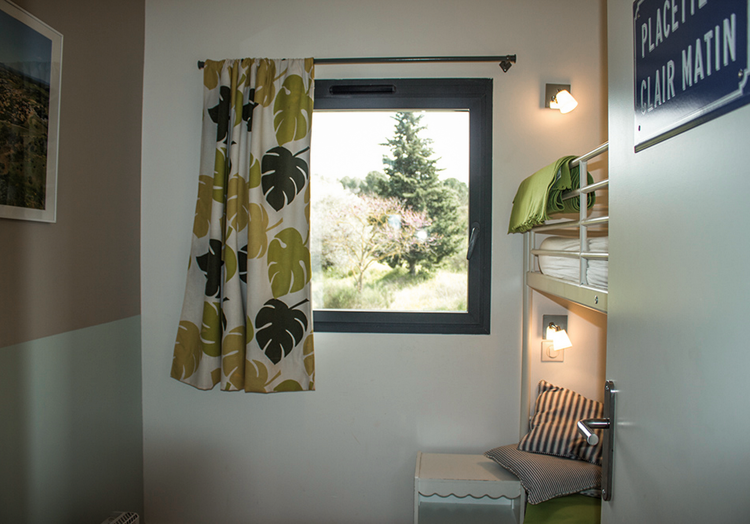 Helles Zimmer mit Einzelbett, Wandleuchte und Fenster