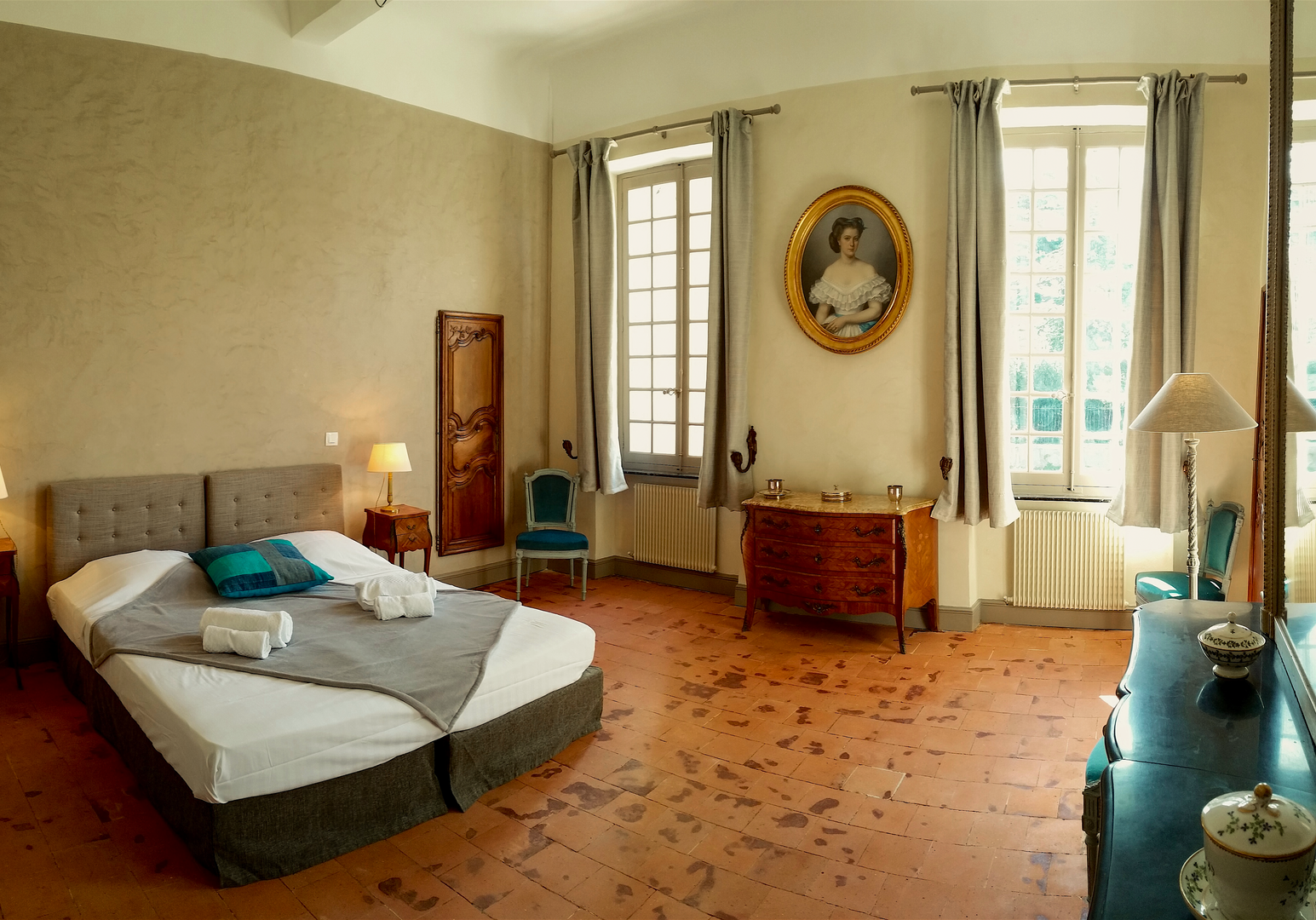 Schlafzimmer mit Doppelbett, Spiegel und Terrakottaboden