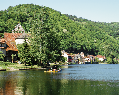 See mit Ufer, Häusern und bewaldeten Hügeln in einer ruhigen Landschaft