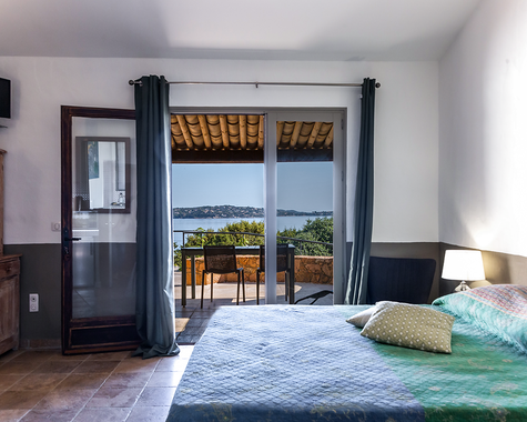 Doppelbett mit grüner Decke, Wandleuchte und Meerblick