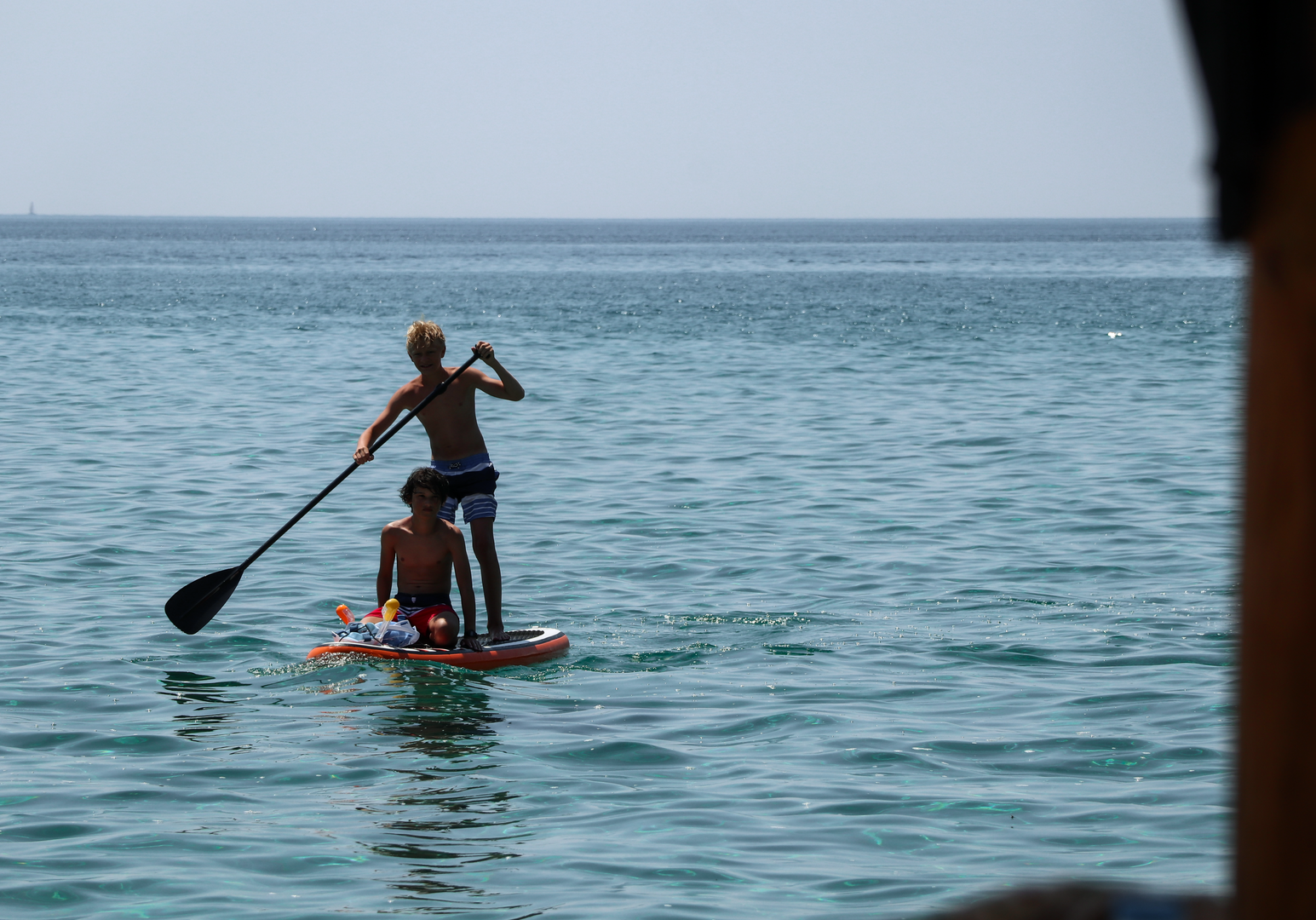 Person paddelt mit Stand-up-Paddle auf ruhigem Meer