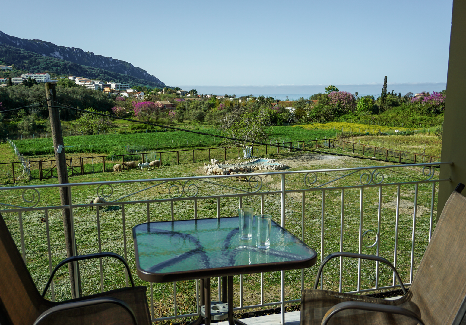Balkon mit Sitzplatz und Blick auf grüne Landschaft und Berge