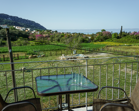 Balkon mit Sitzplatz und Blick auf grüne Landschaft und Berge