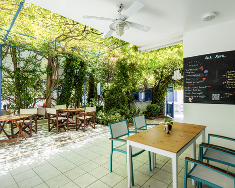 Heller Außenbereich eines Restaurants mit Tischen unter Pergola
