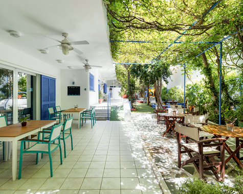 Lange Terrasse mit Sitzplätzen unter begrüntem Dach im Innenhof