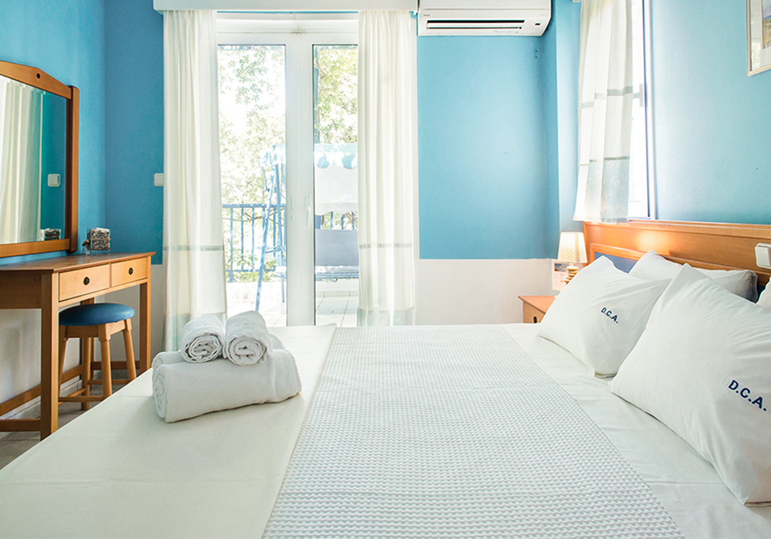 Schlafzimmer mit Doppelbett, türkisen Akzenten und Fenster
