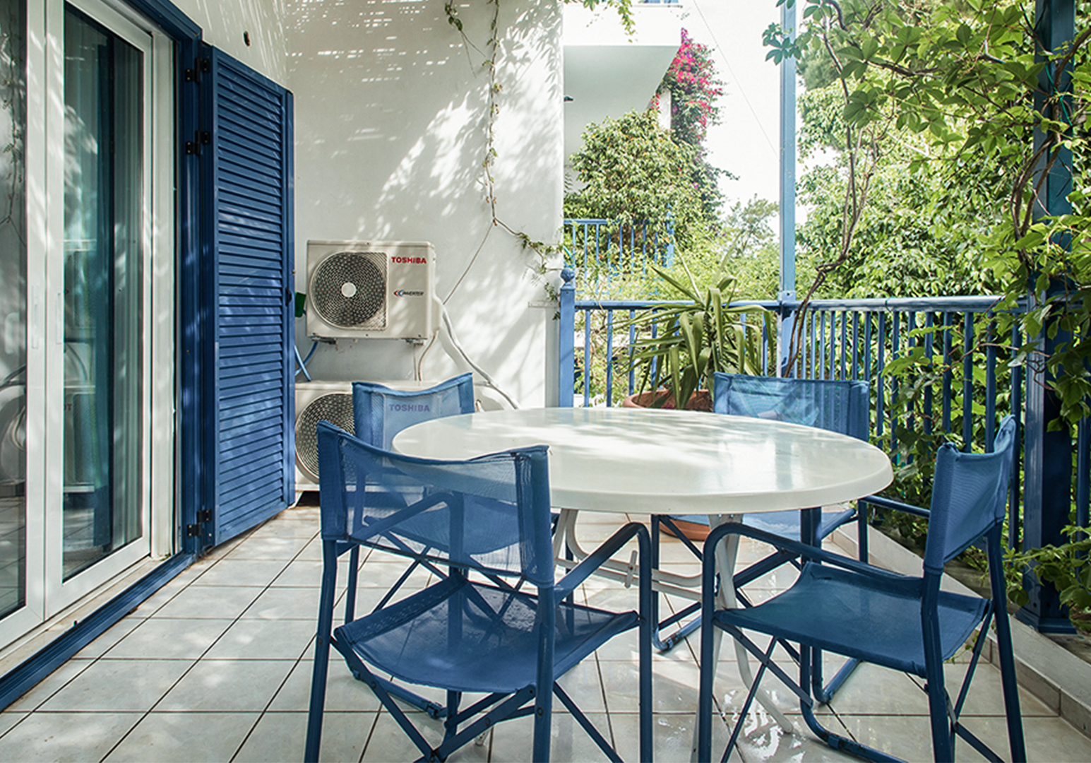 Balkon mit blauen Stühlen, Tisch und Gartenblick