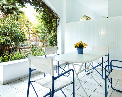 Terrasse mit weißen Stühlen, Tisch und Gartenblick