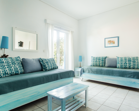 Wohnbereich mit türkisem Sofa, Couchtisch und hellem Fenster