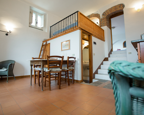 Wohnbereich mit Sofa, Esstisch und Treppenaufgang