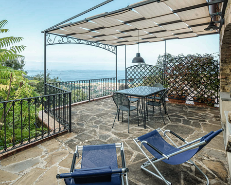 Terrasse mit Liegestühlen, Pergola und Ausblick auf das Meer.