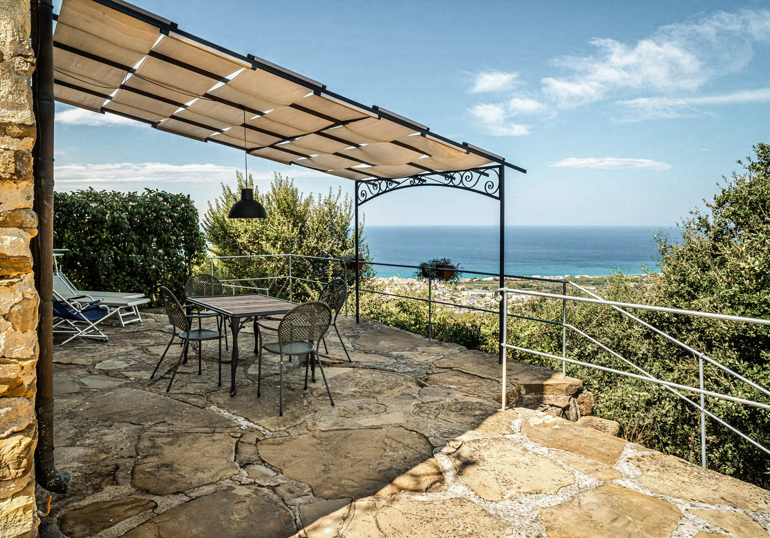 Überdachte Terrasse mit Sitzgelegenheiten und Blick auf das Meer.