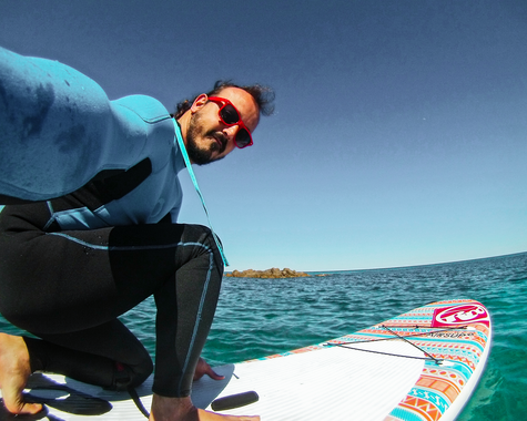 Person mit Surfbrett auf dem Meer bei sonnigem Wetter.