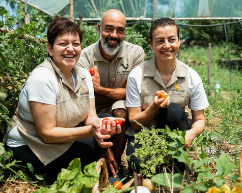 Drei Personen sitzen gemeinsam lachend im Garten