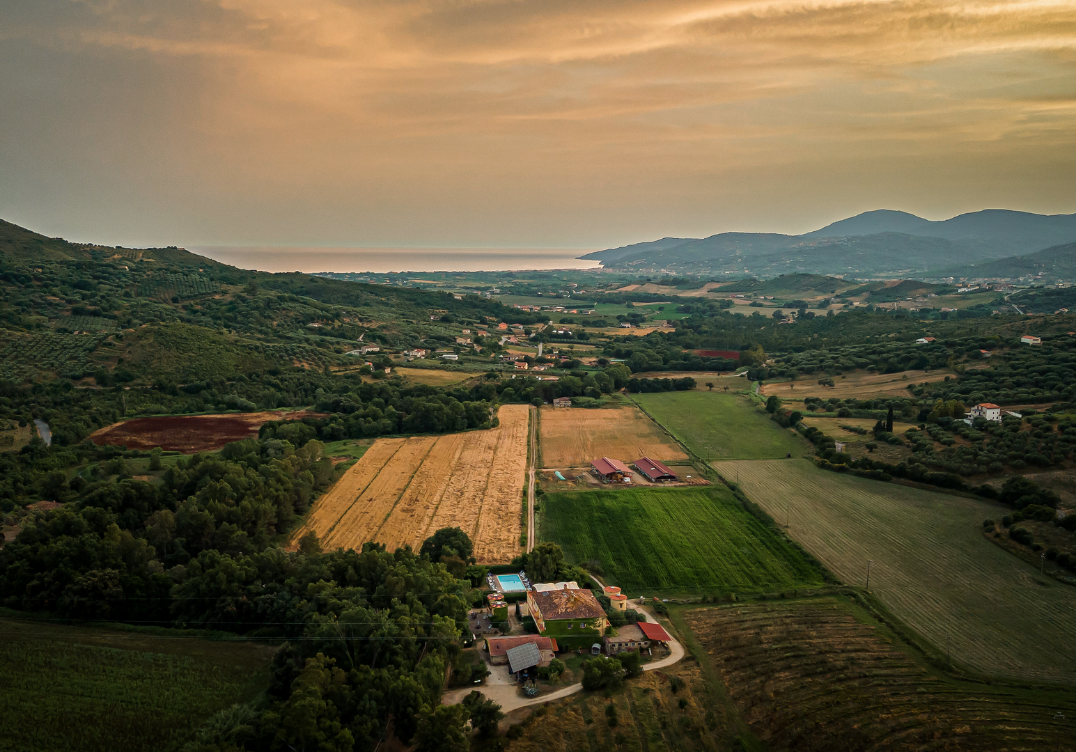 Weite Landschaft mit Feldern und Bergen bei Sonnenuntergang