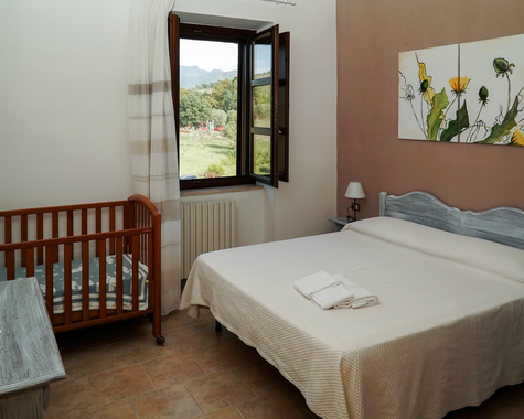Schlafzimmer mit Doppelbett und Babybett sowie Zugang zum Balkon