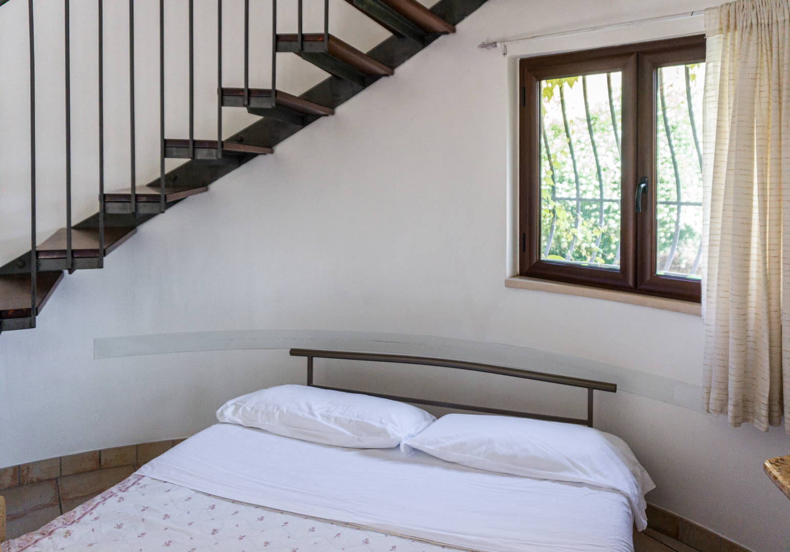 Schlafzimmer unter Treppe mit Bett und Fenster
