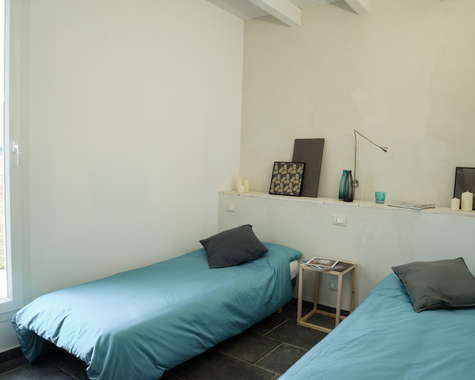 Schlafzimmer mit zwei Betten, türkiser Bettwäsche und Fenster