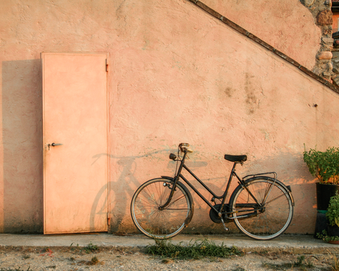Fahrrad vor einer rosafarbenen Hauswand.