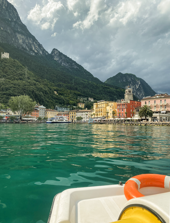 Blick von einem Boot auf einen Bergsee und einen Ort am Ufer.