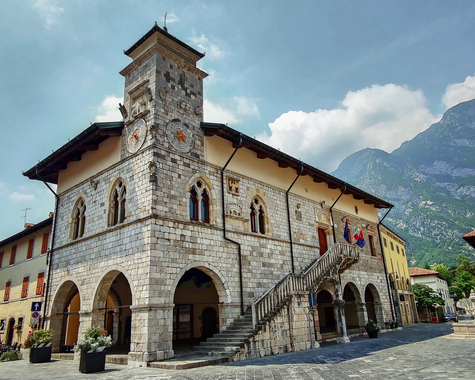 Historisches Rathaus auf einem Platz vor einer alpinen Bergkulisse.