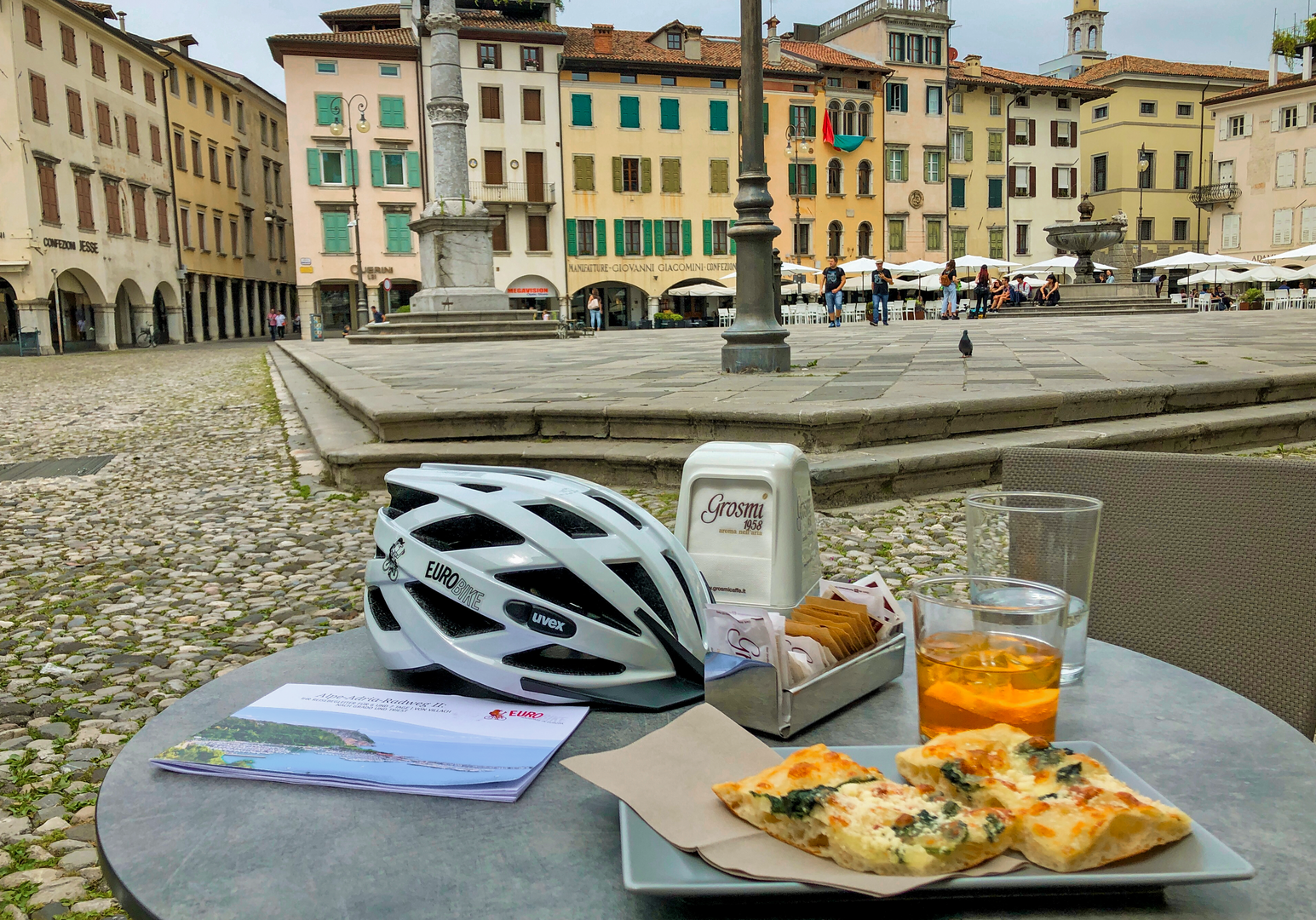 Fahrradhelm und Imbiss auf einem Tisch eines Marktplatzcafés.