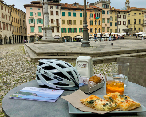 Fahrradhelm und Imbiss auf einem Tisch eines Marktplatzcafés.