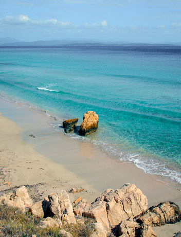 Kleiner Sandstrand mit kristallklarem Wasser an einer geschützten Küste.
