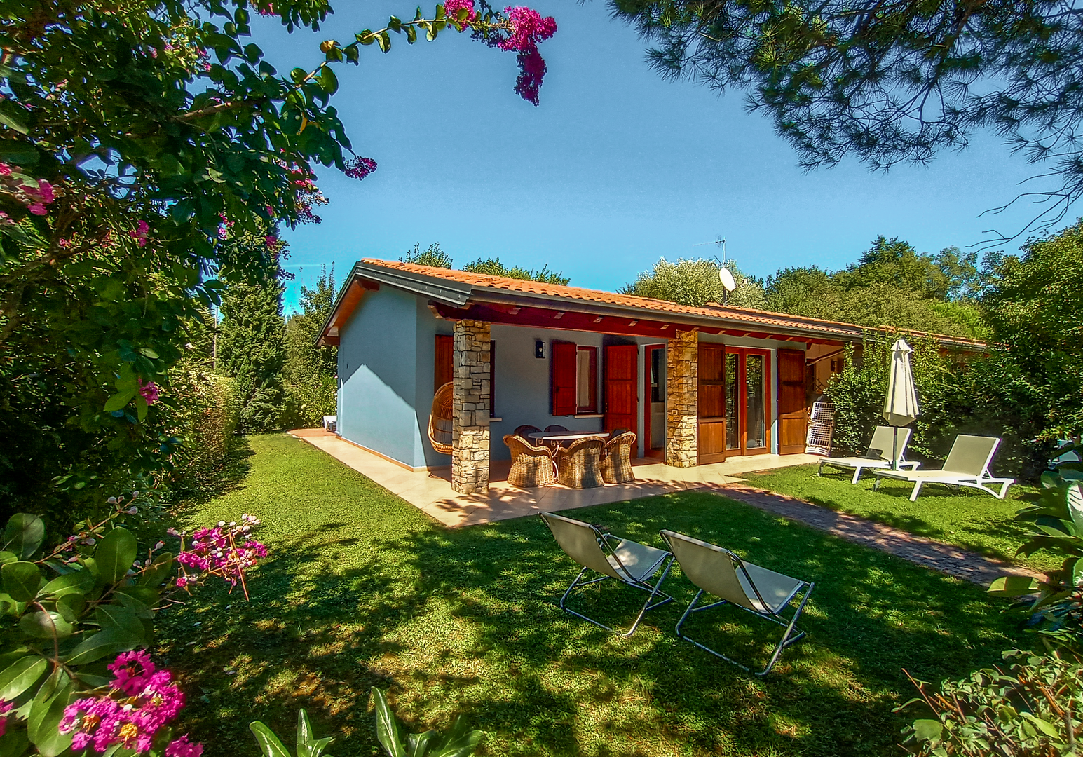 Helles Ferienhaus mit Veranda, eingebettet in einen blühenden mediterranen Garten.