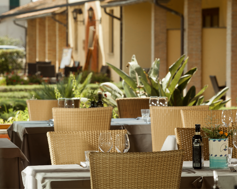 Gemütliche Terrasse mit gedeckten Tischen und Blick auf die Gartenanlage der Unterkunft.