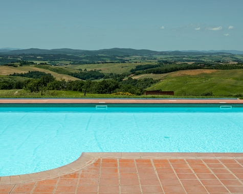 Sonnenterrasse am Pool mit freiem Blick über Felder und sanfte Hügel.