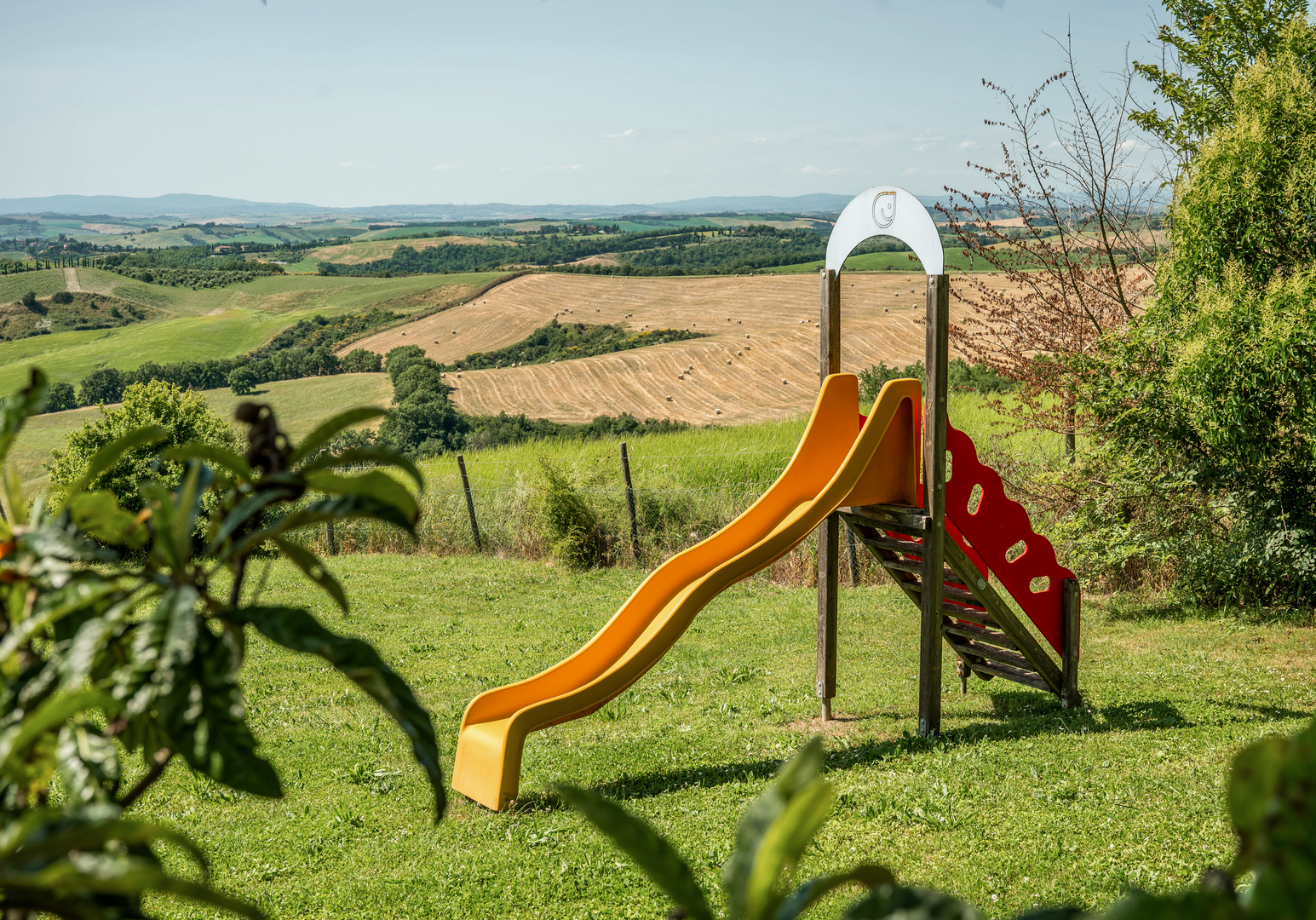 Rutsche und Spielgerät auf einer Wiese mit freiem Blick über die umliegende Landschaft.