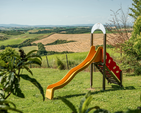 Rutsche und Spielgerät auf einer Wiese mit freiem Blick über die umliegende Landschaft.