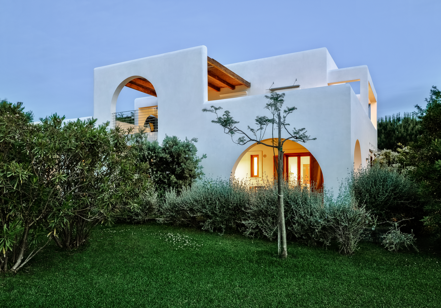 Weißes Ferienhaus mit mediterraner Architektur, umgeben von gepflegten Gärten und Pflanzen.